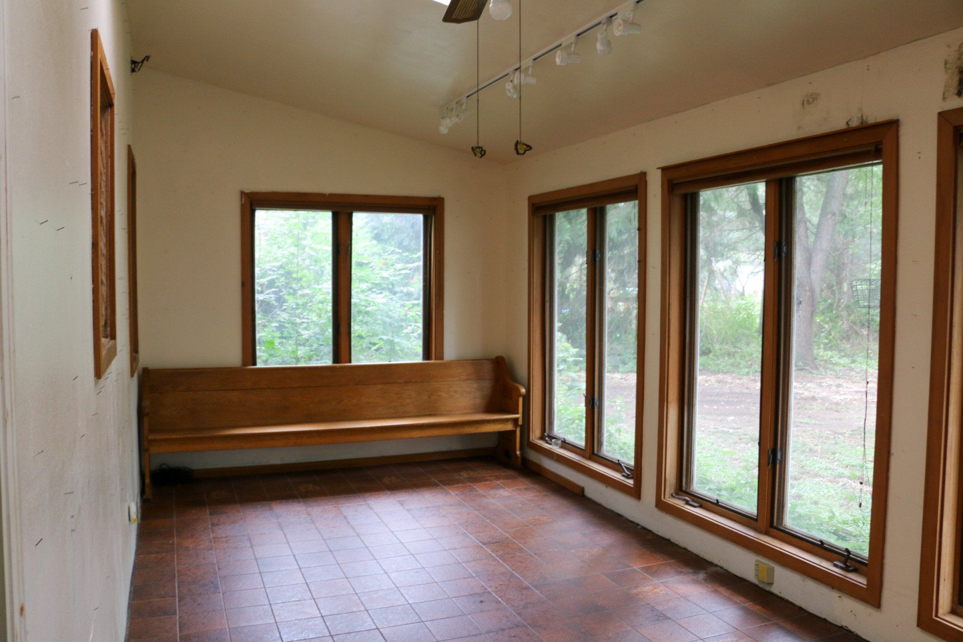 An empty room with a wooden bench and lots of windows