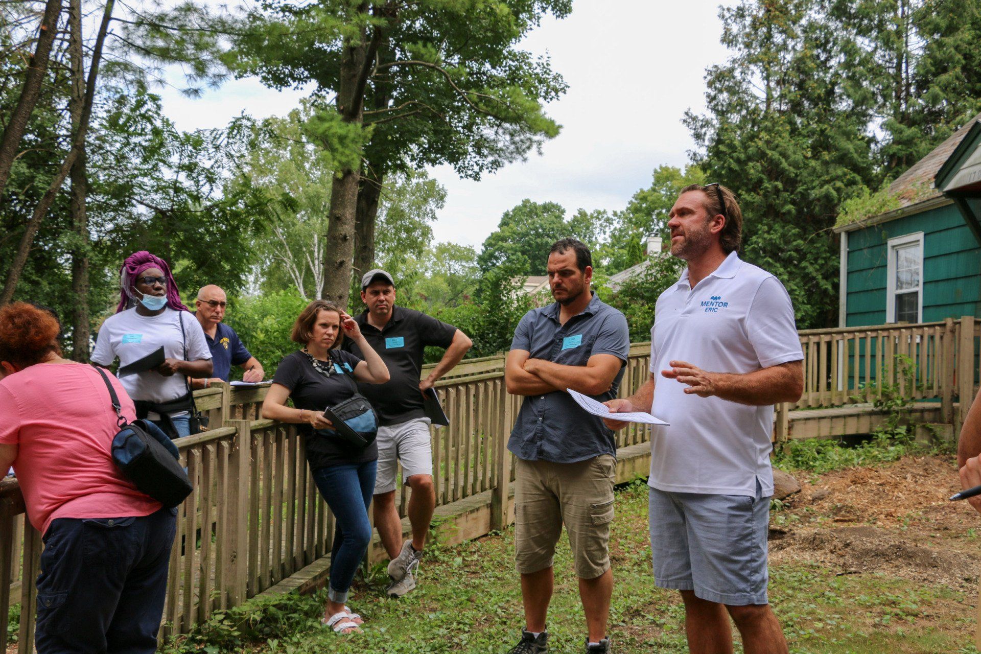 A group of people are standing in front of a wooden fence.