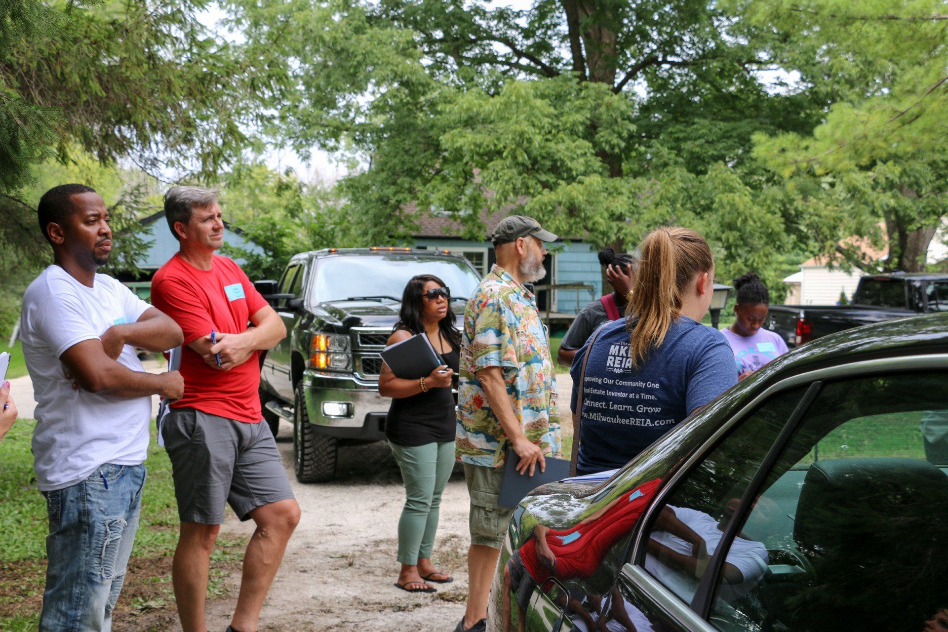 A group of people are standing around a car on a dirt road.