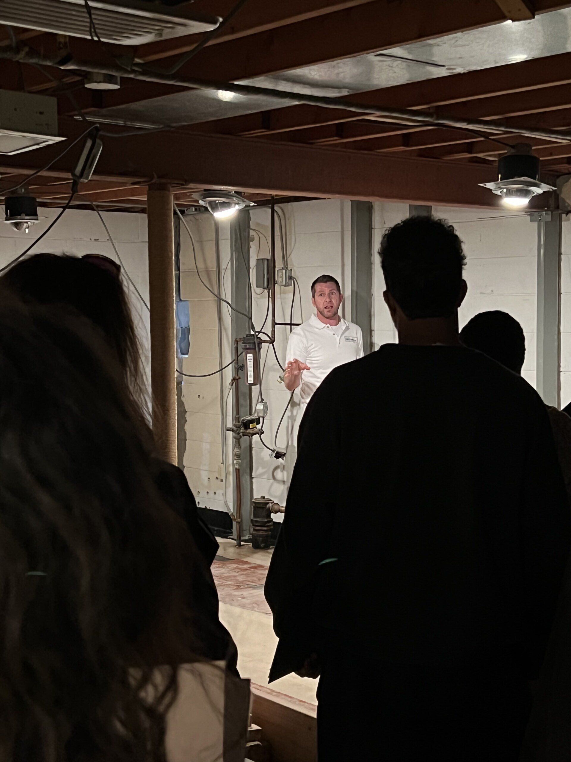 A group of people standing in a dark room with a man standing in the background