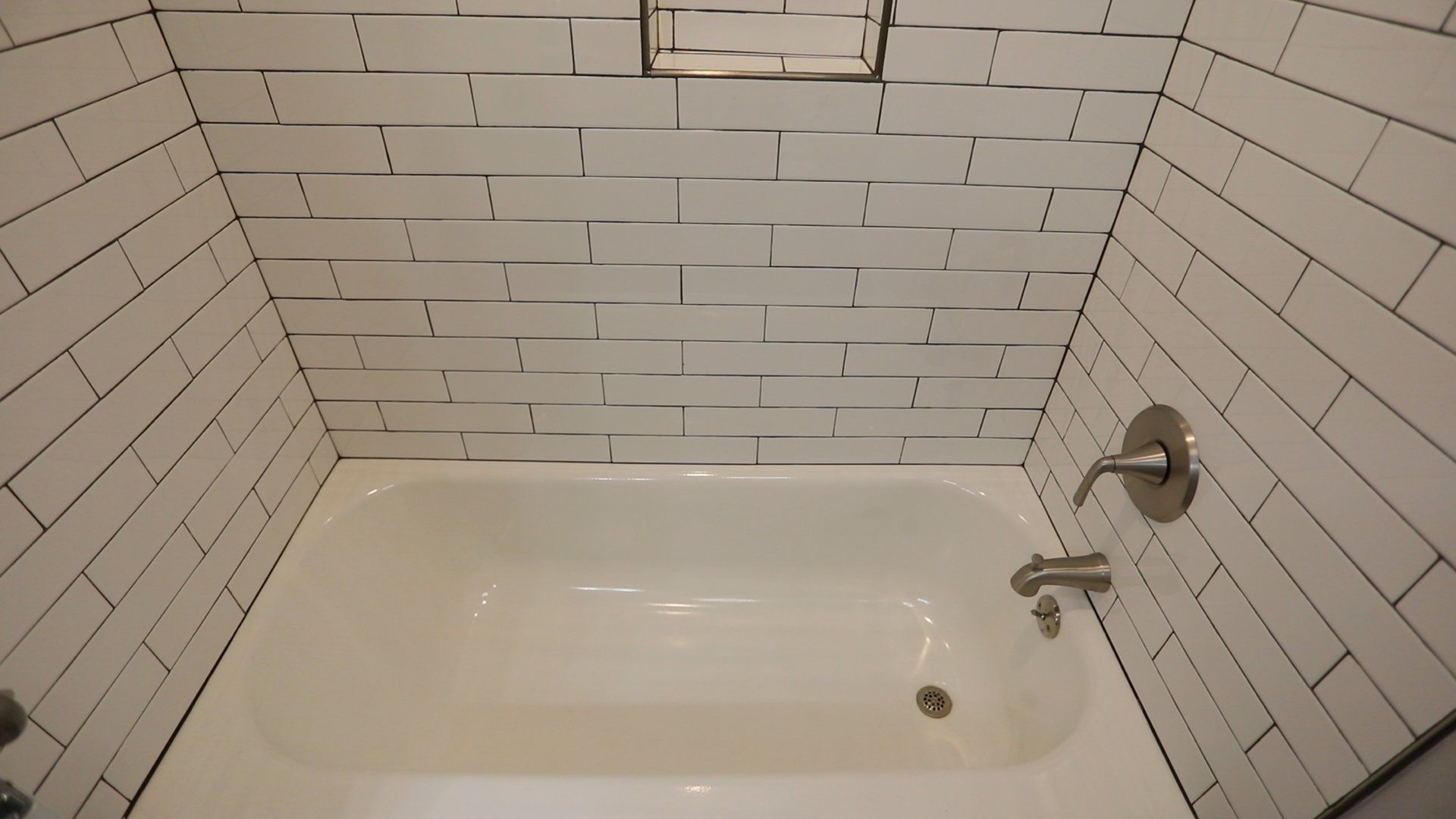 A bathtub in a bathroom with white brick walls