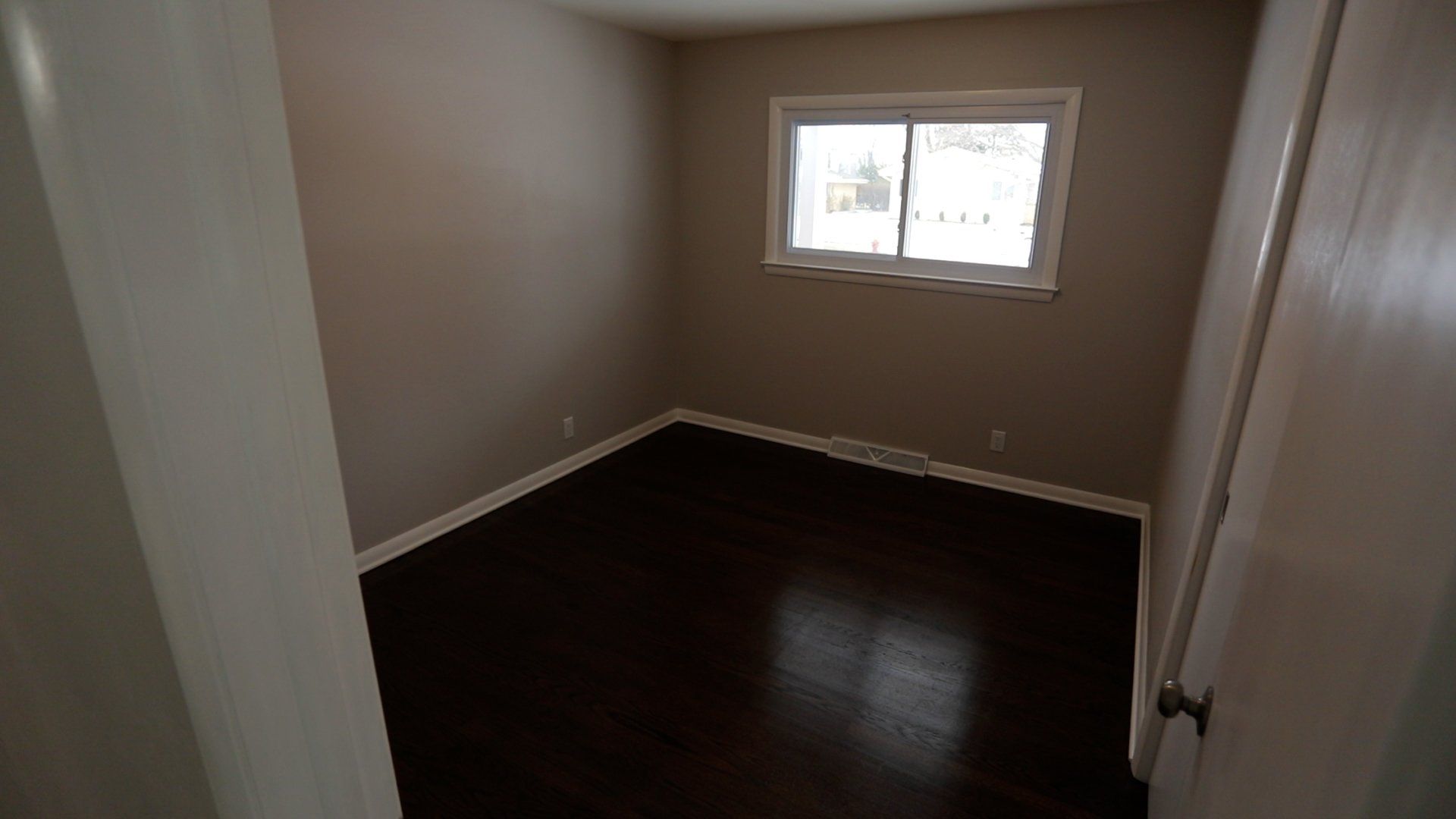 An empty room with hardwood floors and a window
