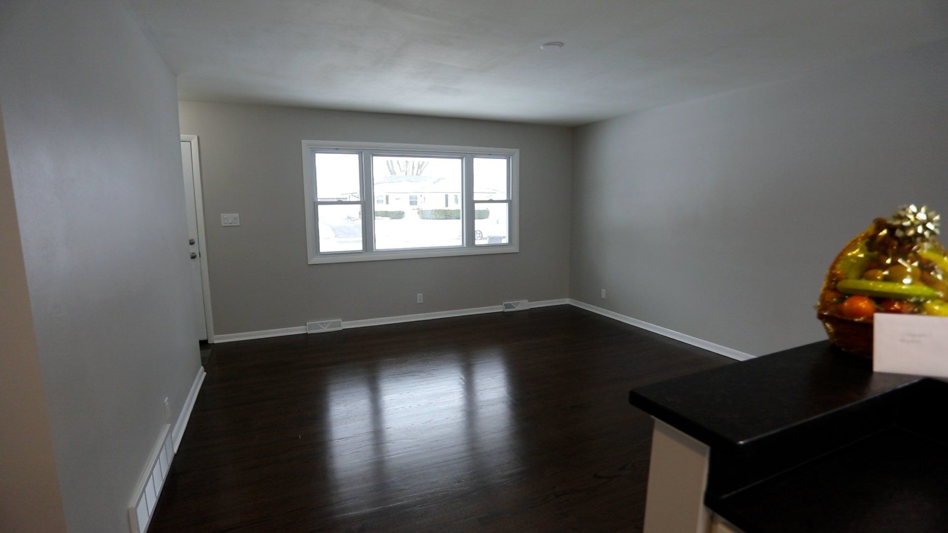An empty living room with a bowl of fruit on the counter
