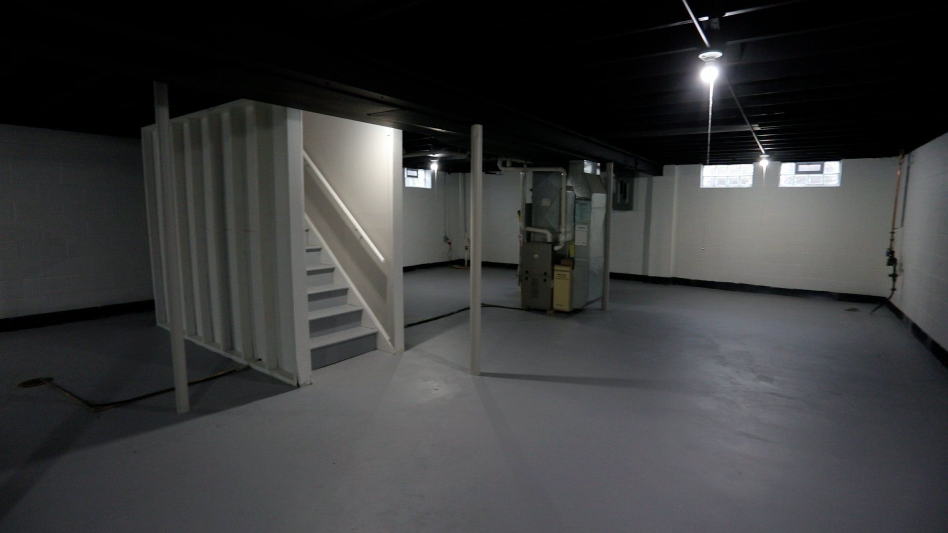 An empty basement with stairs leading up to the second floor.