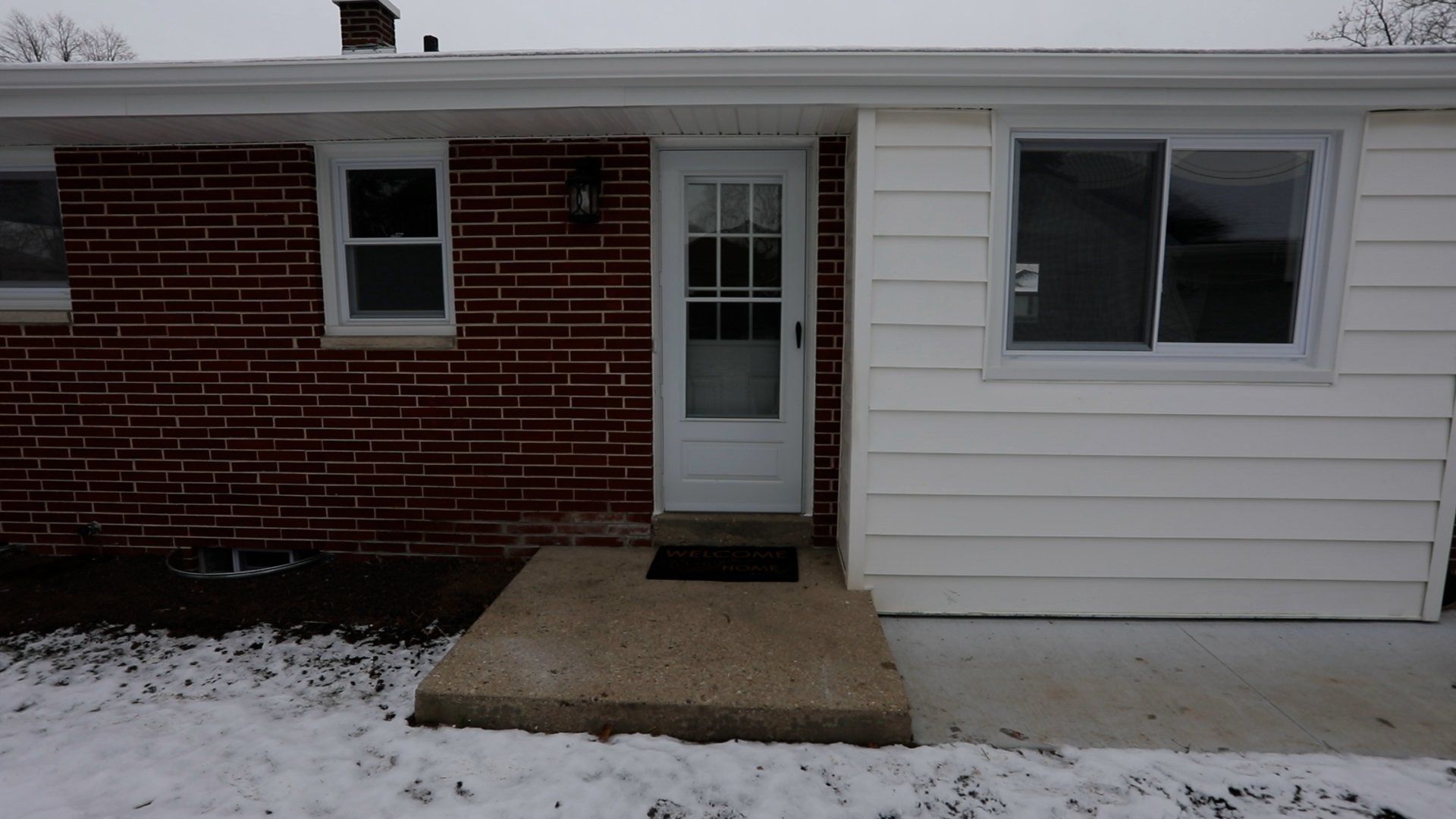 A brick house with a white siding and a sliding glass door