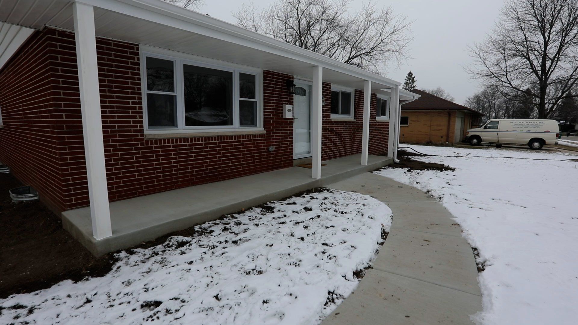 A brick house with a porch and snow on the ground