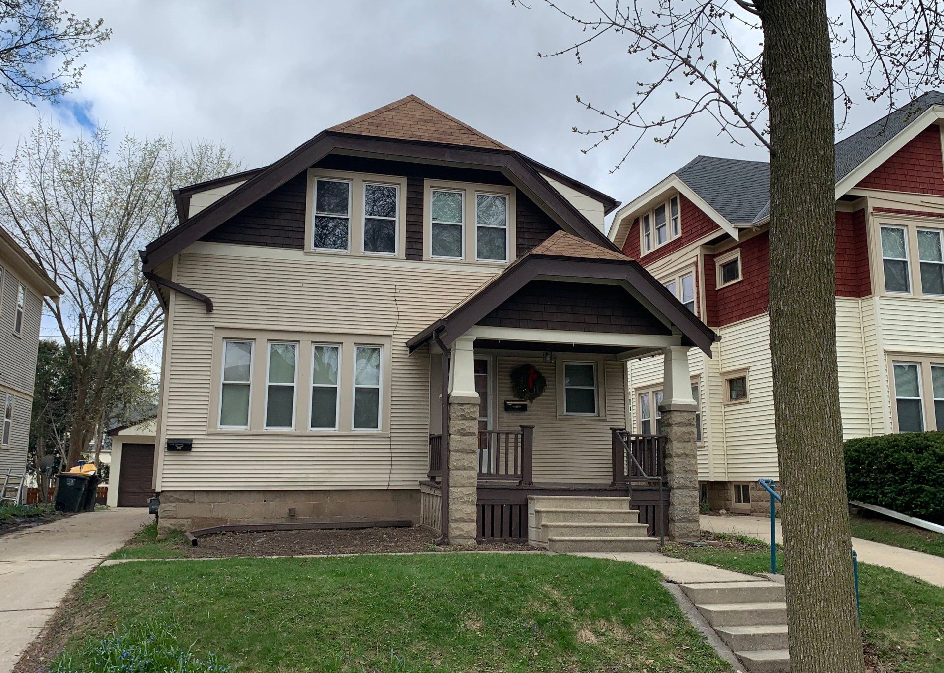 A white house with a brown roof is next to a red house