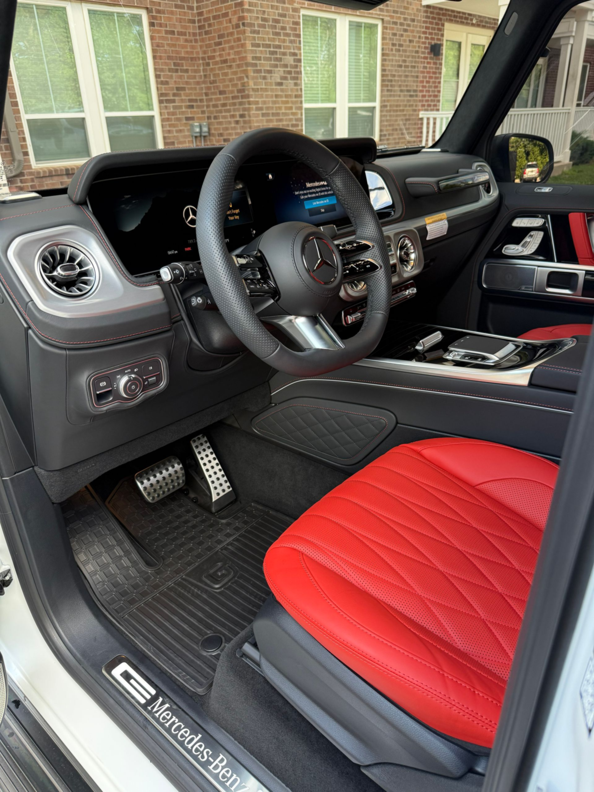 Sports car interior with black dashboard and steering wheel, red-and-black seats, and open driver’s door