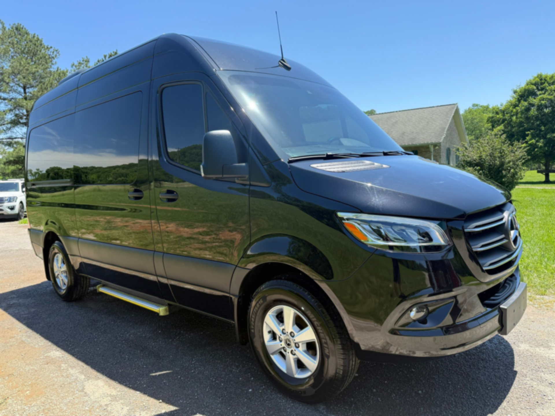 Black cargo van parked outdoors on a sunny driveway, side view