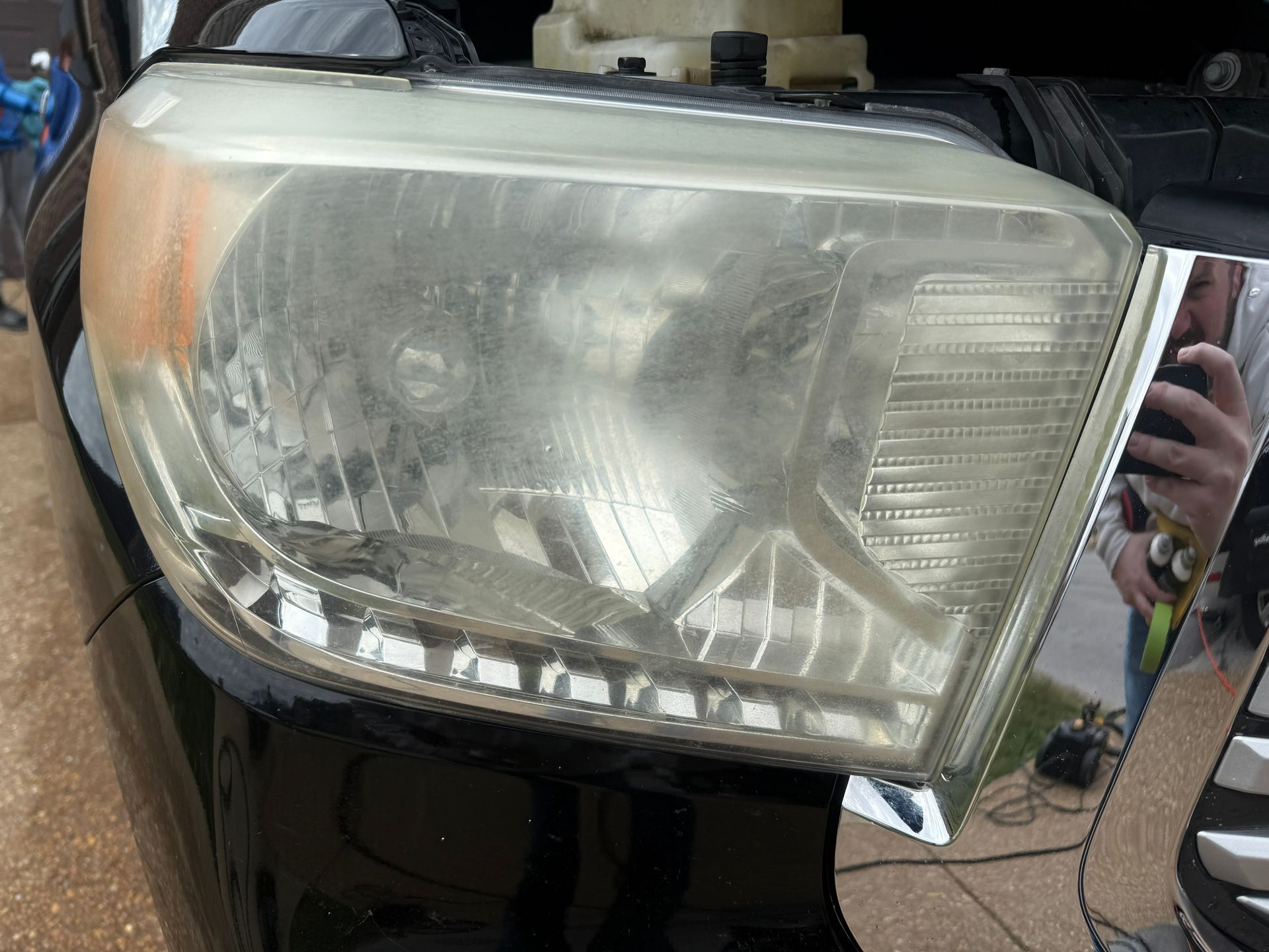 Close-up of a red car’s front headlight with the hood open