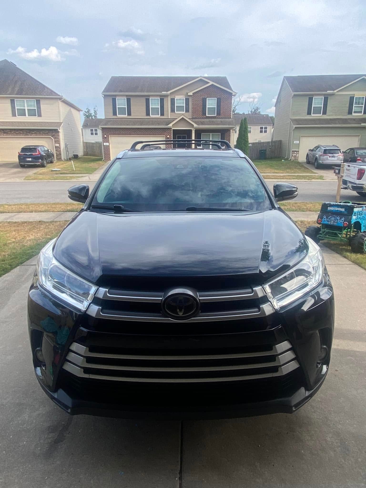 Black SUV parked in a suburban driveway with houses in the background