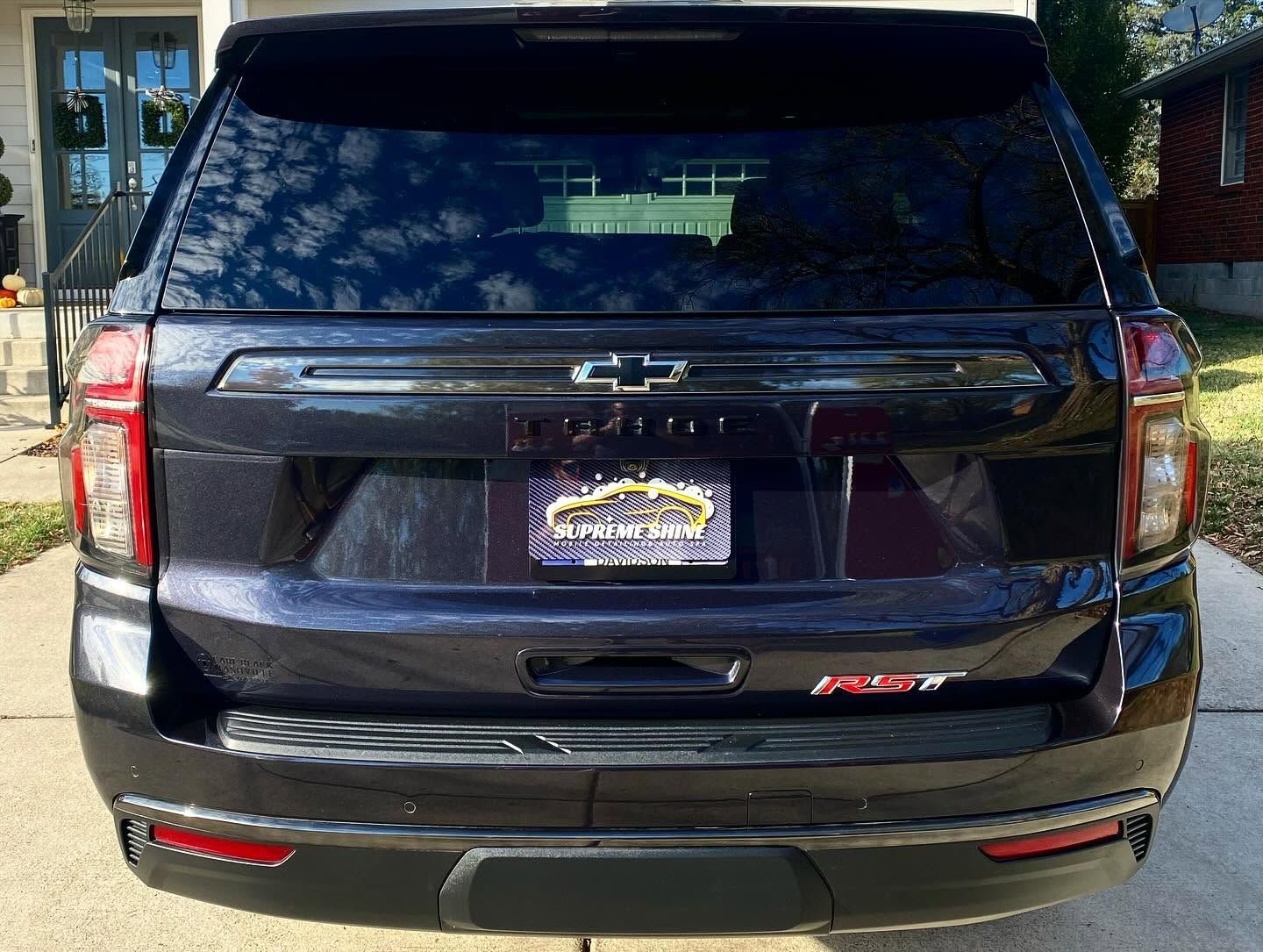 Rear view of a black Chevrolet SUV parked outdoors, with tinted windows and a dealer plate.