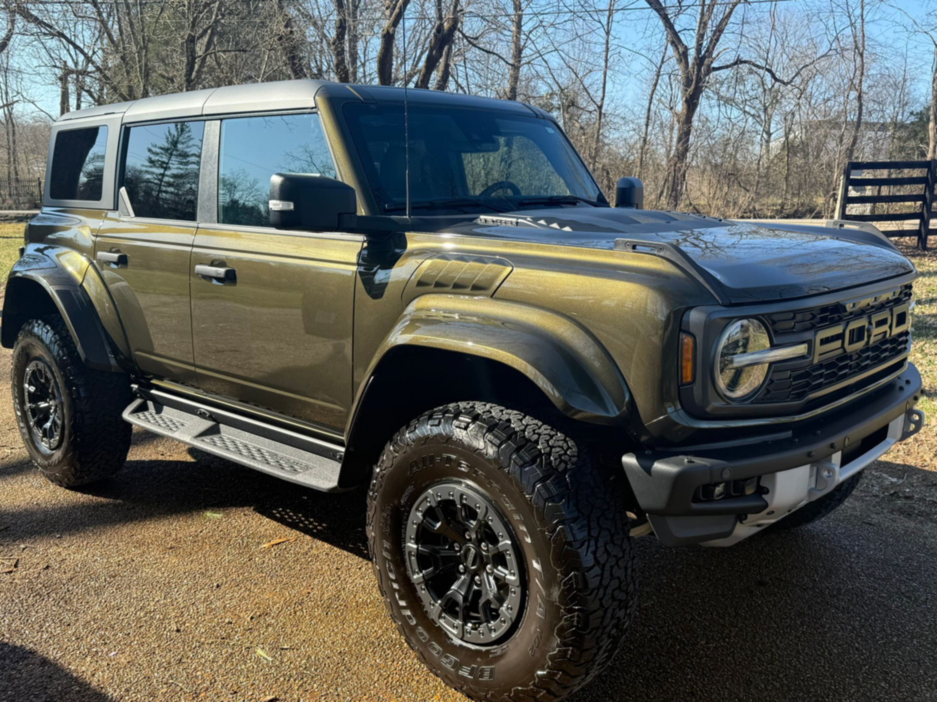 Olive green Bronco SUV parked outdoors on a dirt lot, with black wheels and off-road tires.
