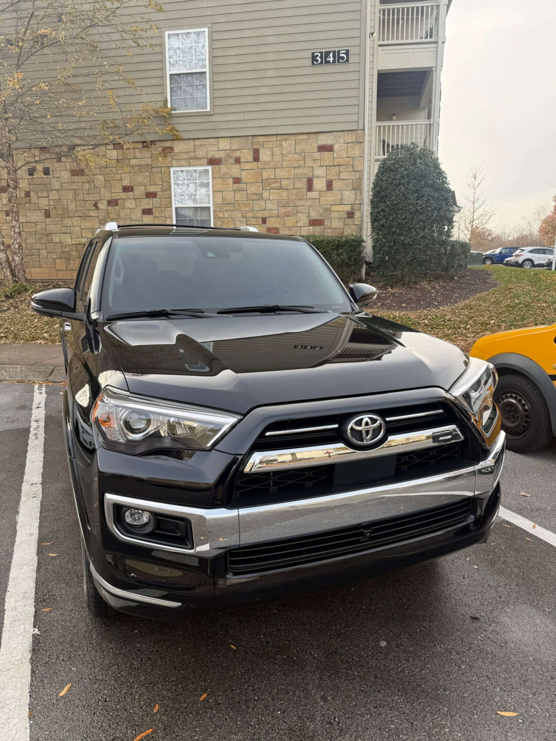 Black Toyota SUV parked in front of an apartment building on a wet street.