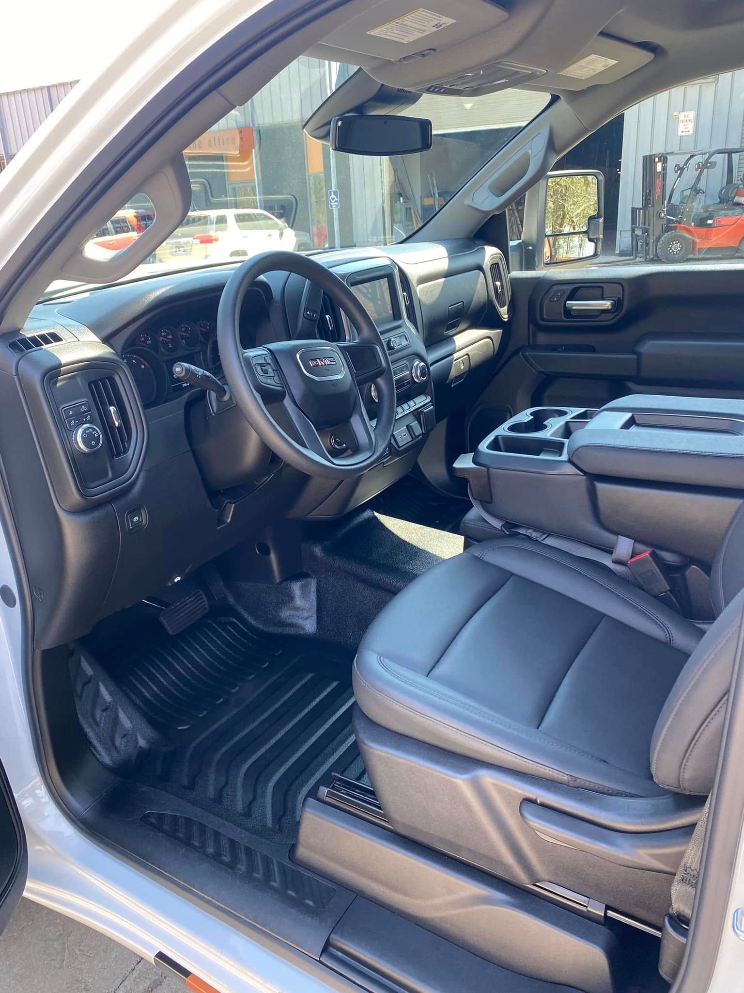 SUV interior with black leather seats and driver’s cockpit visible, front door open