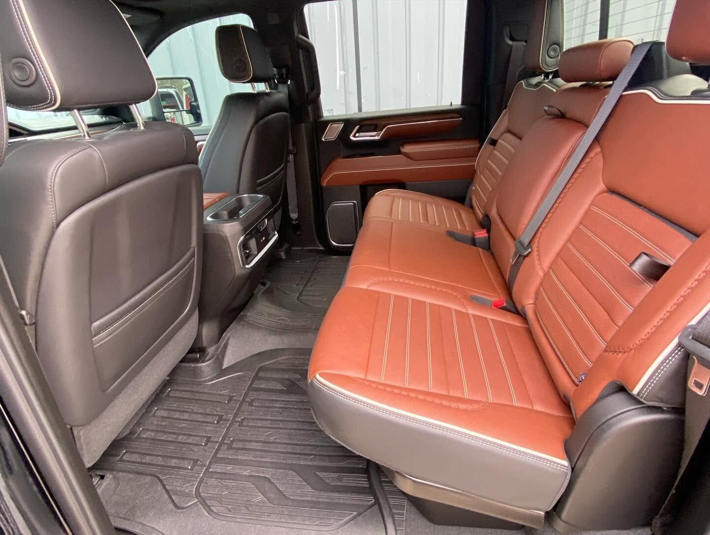 Interior of a van with orange-and-brown leather rear seats and rubber floor mats