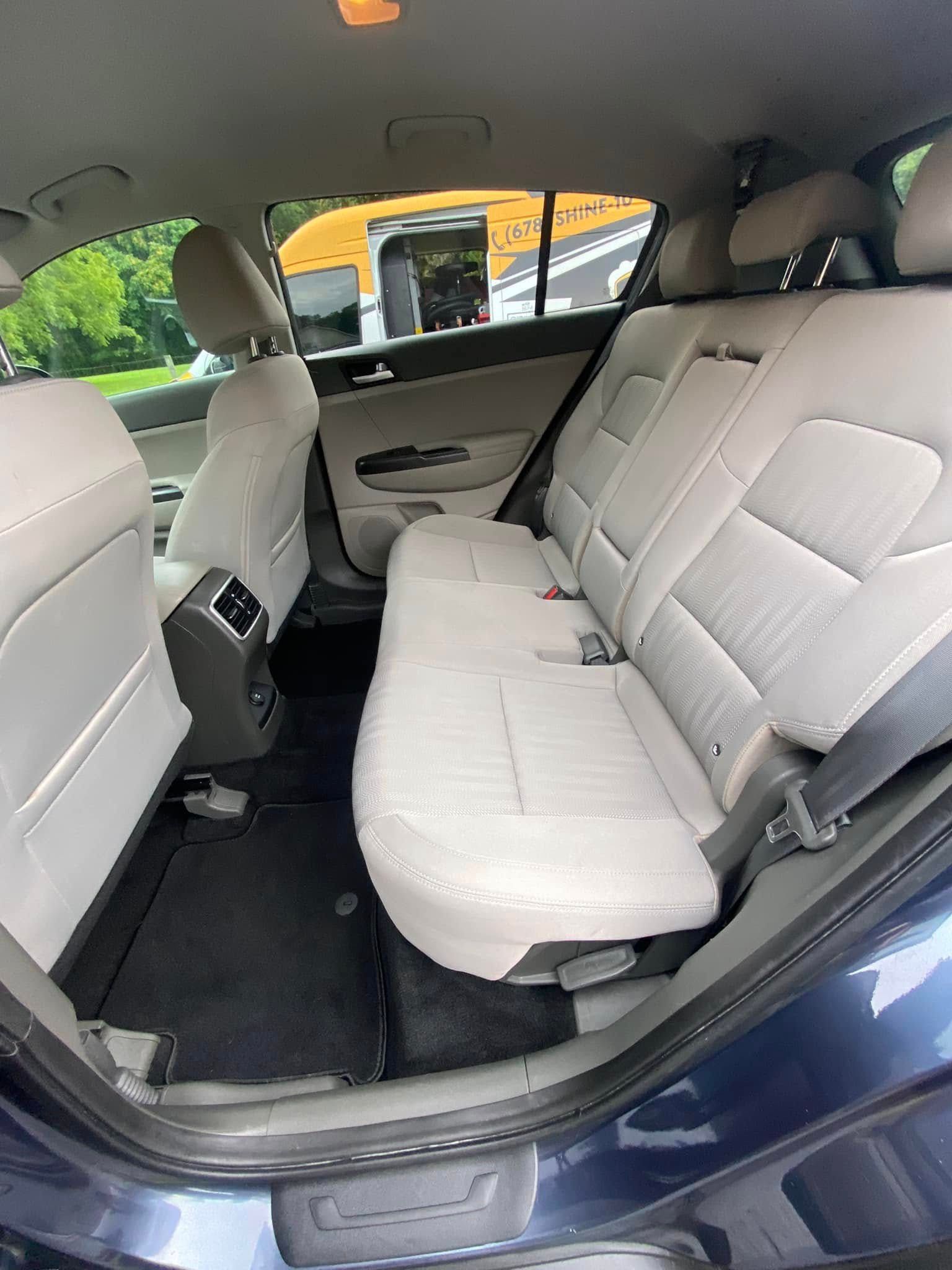 Back seat of a blue car with beige upholstery and folded-down rear seat access