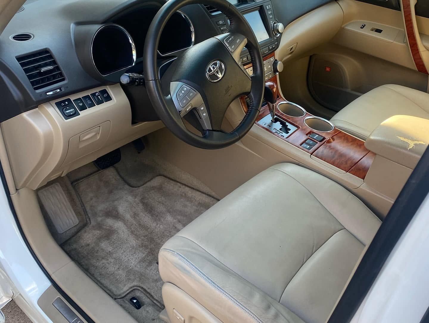 Tan interior of a luxury car with leather seats, wood trim, and a visible steering wheel and dashboard