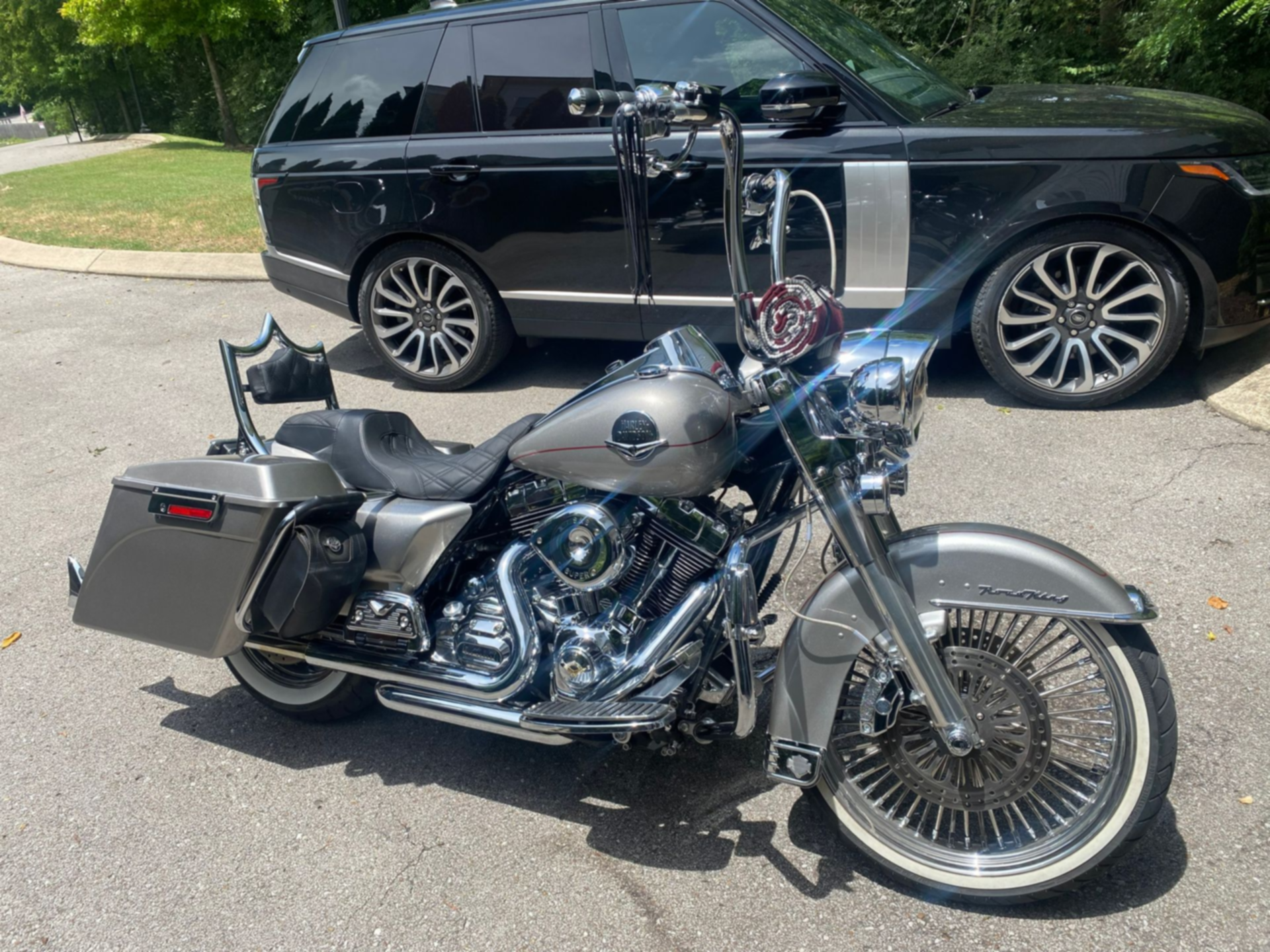 Chrome motorcycle parked in front of a black SUV on a residential street