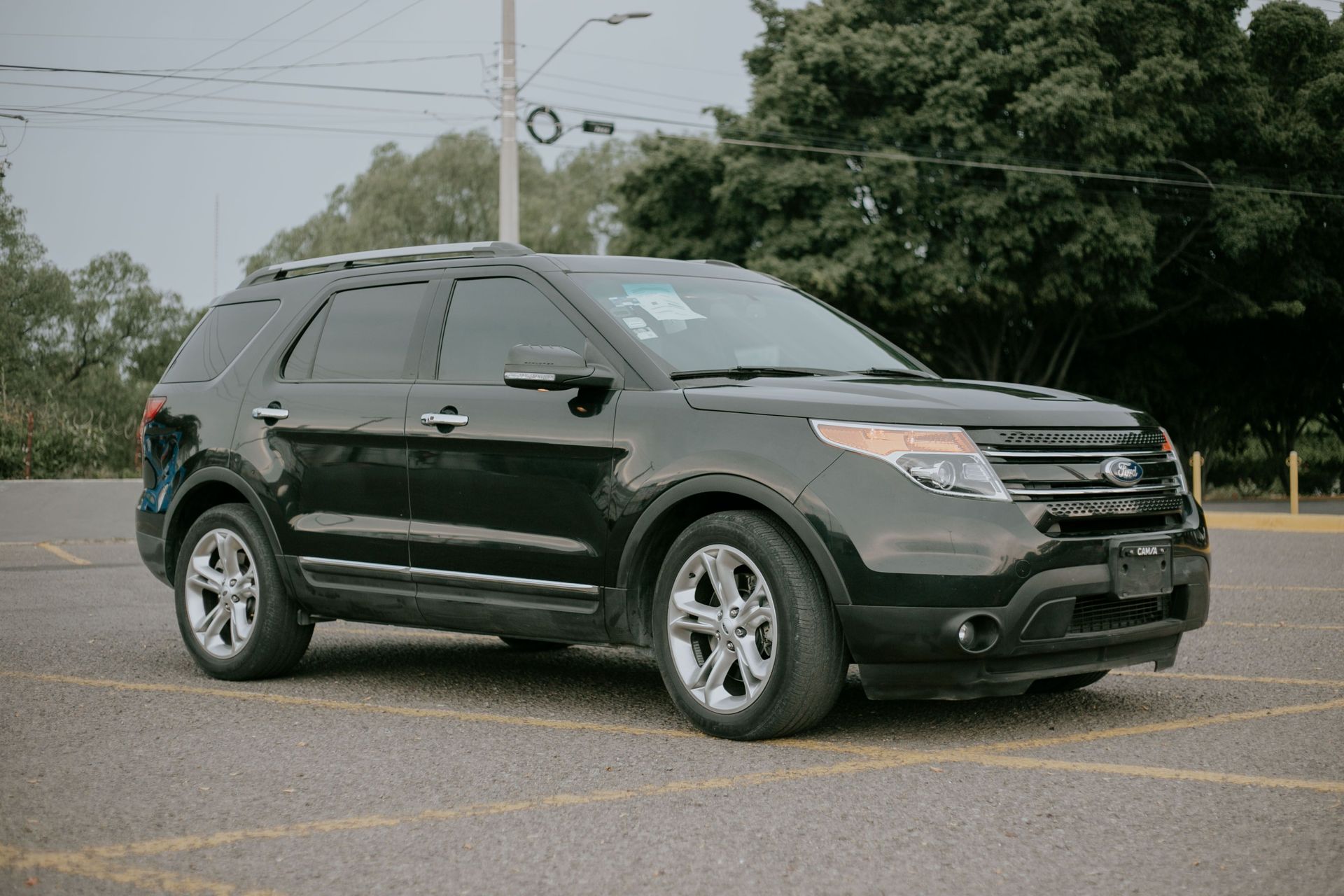Black SUV parked on a wet road near trees and power lines