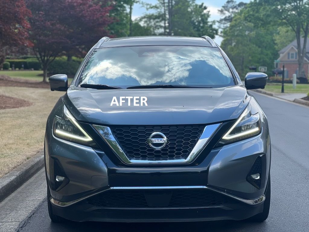 Front view of a gray Nissan SUV with “AFTER” on the hood, parked on a suburban street.