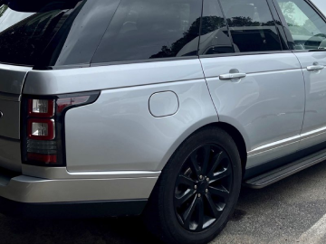 Silver SUV parked outdoors, rear side view with black wheels and tinted windows