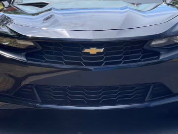 Front view of a black Chevrolet car with a gold bowtie emblem and grille.