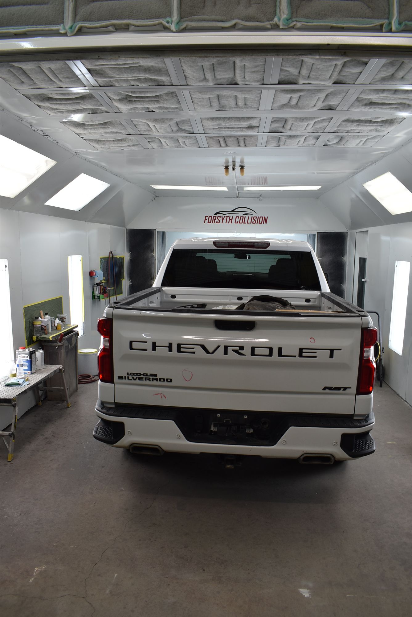 White Chevrolet pickup truck in a bright garage, viewed from the rear.