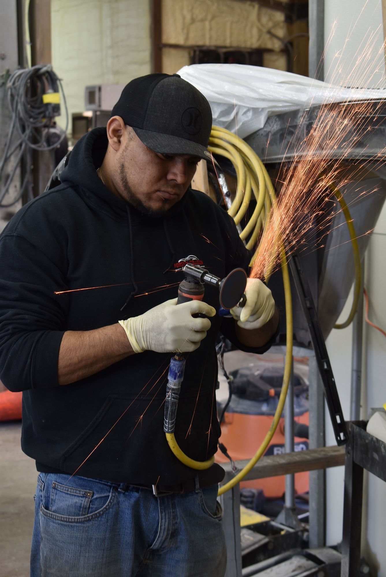 Worker using an angle grinder, sending sparks in a workshop.