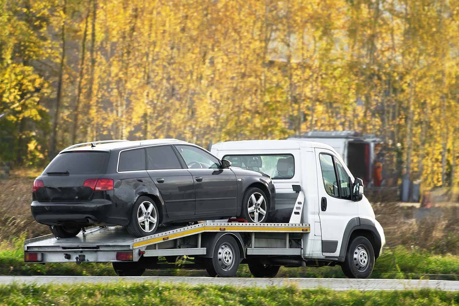 A Black Car Being Towed by a White Tow Truck on a Road — A1 Loco's Towing in Gladstone, QLD