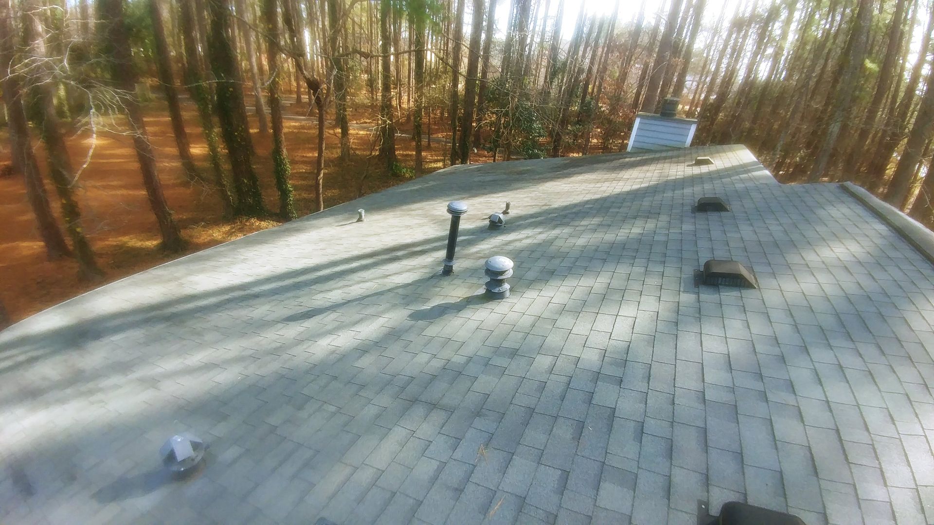 A roof with a lot of vents on it and trees in the background