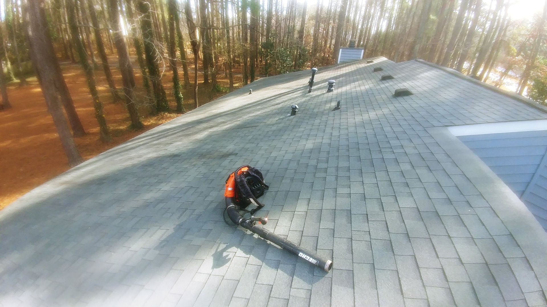 A person is working on a roof with a blower.
