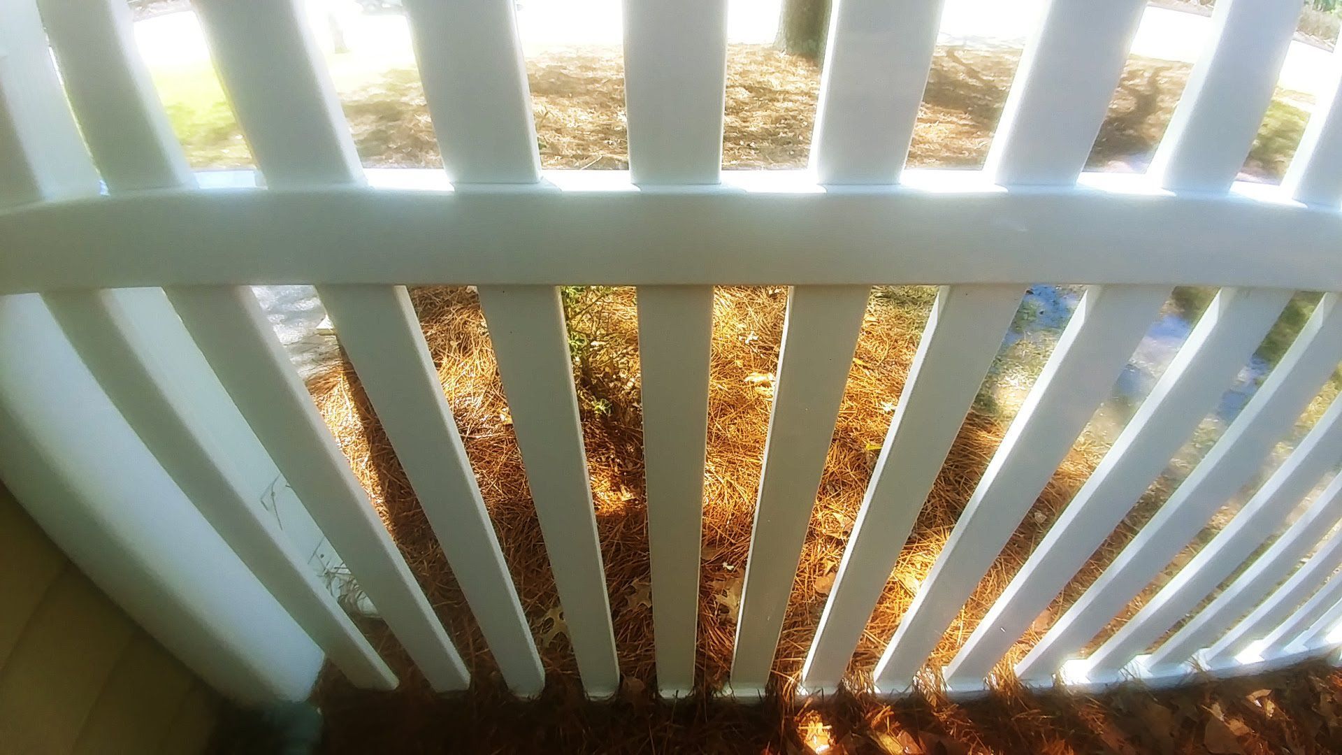 A white fence with a lot of leaves on it