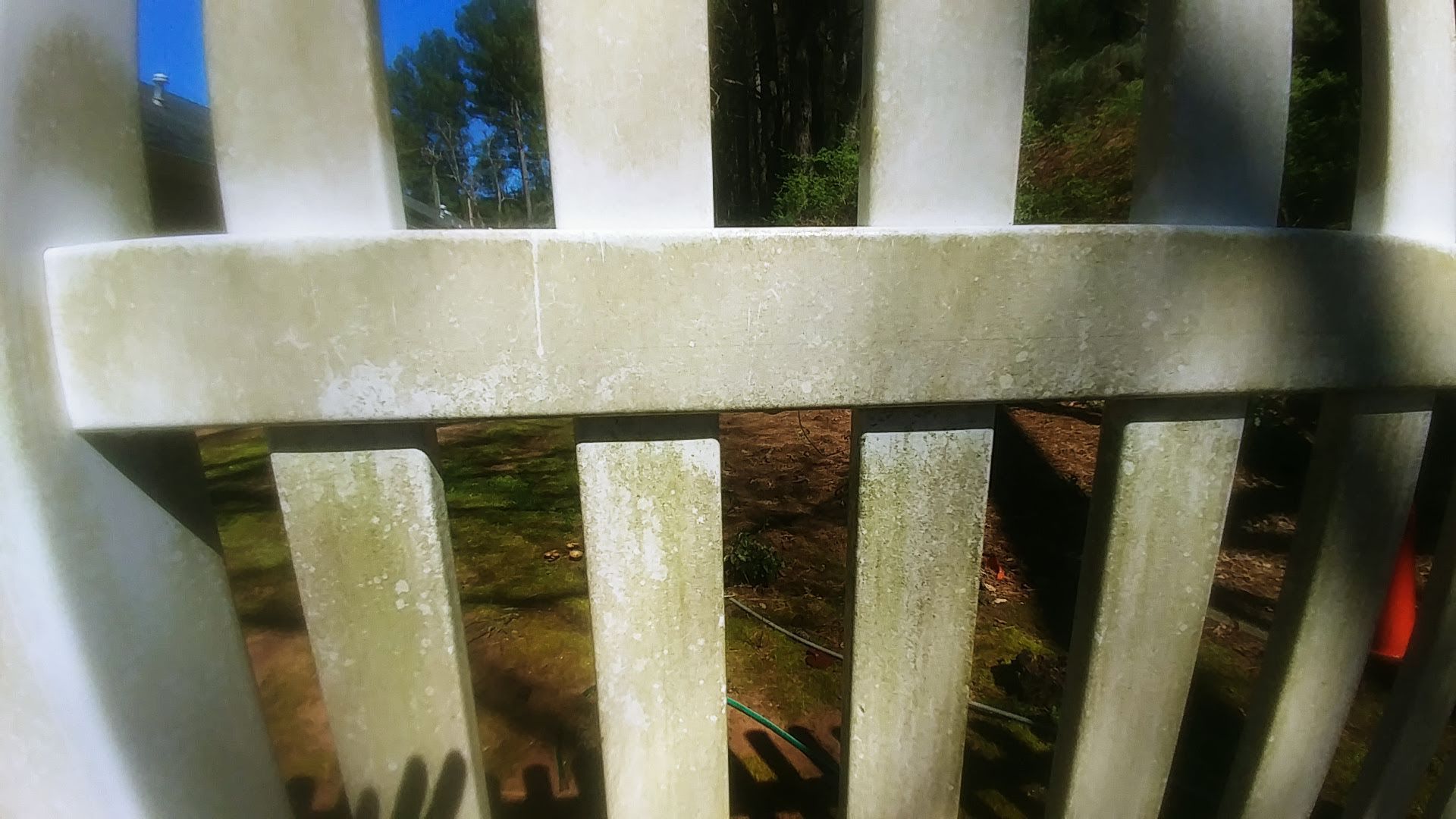 A close up of a white picket fence with trees in the background.