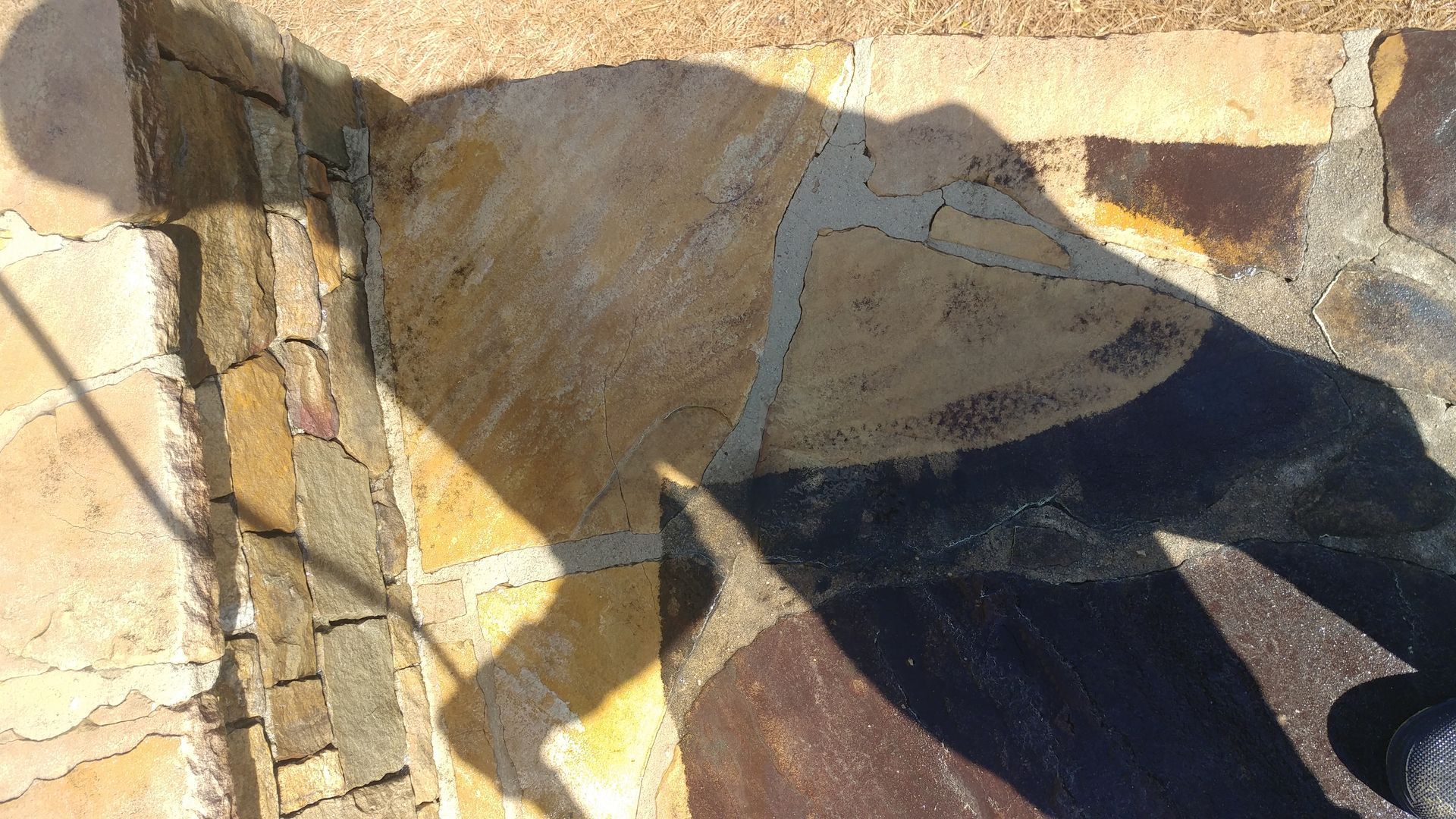 A shadow of a person is cast on a stone wall