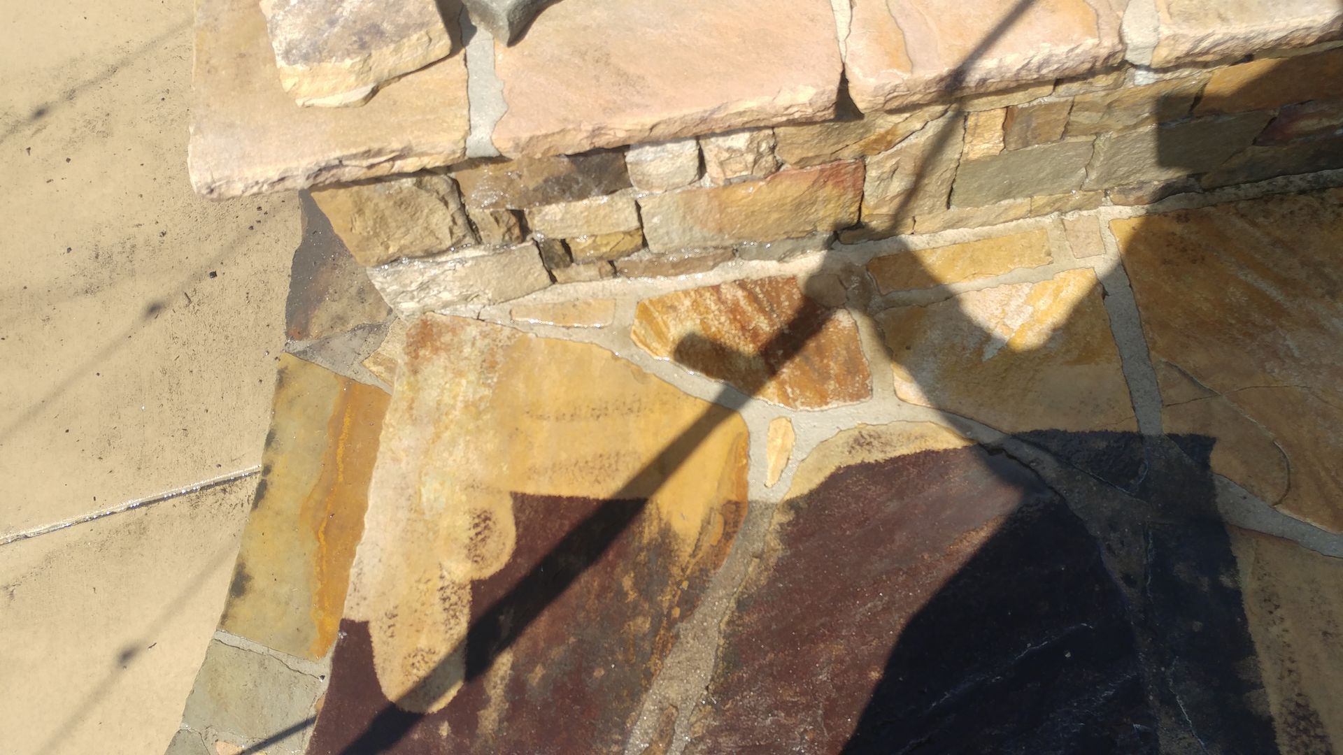 A shadow of a person is cast on a stone wall.