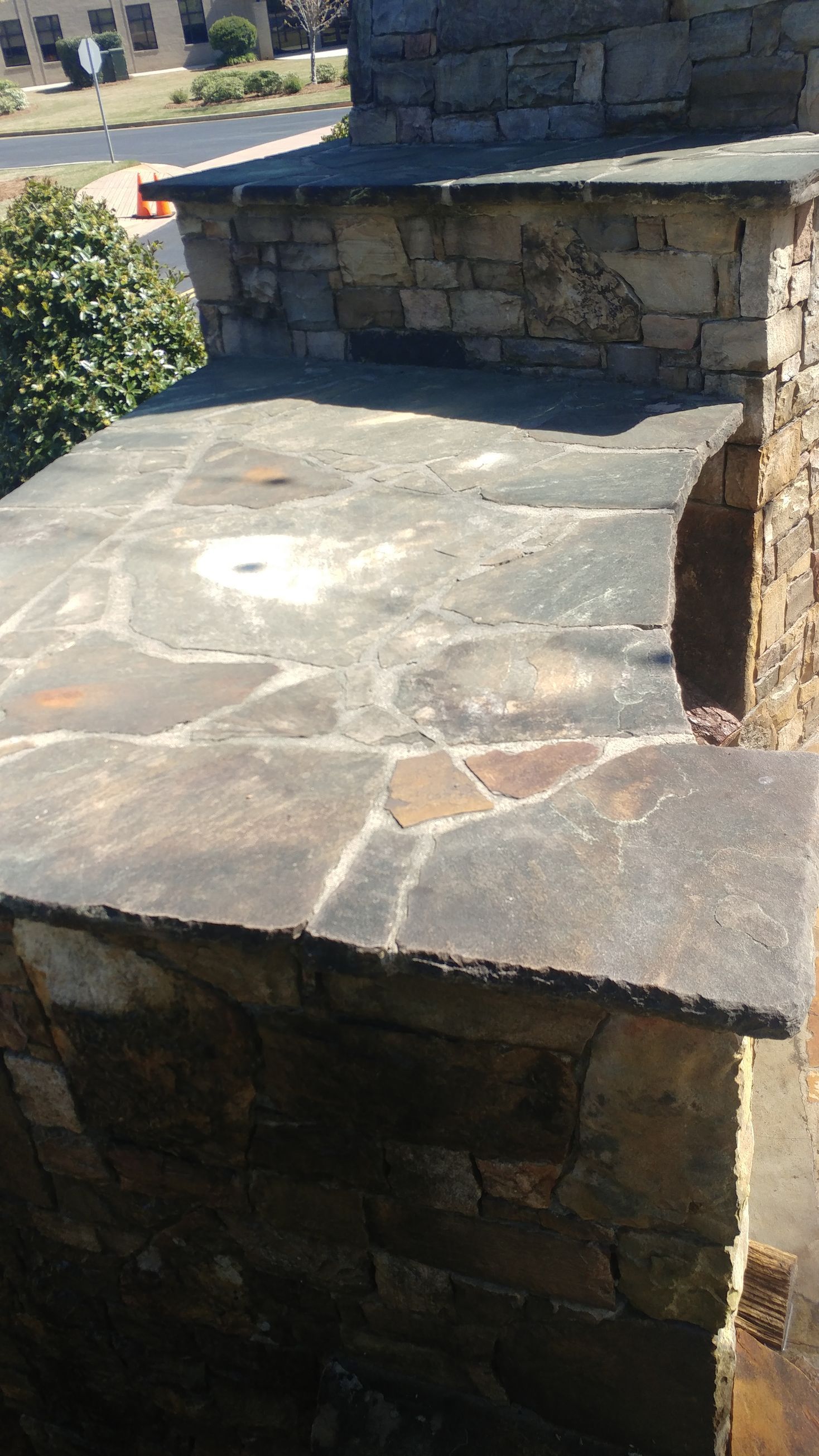 A stone patio with a fireplace in the background.