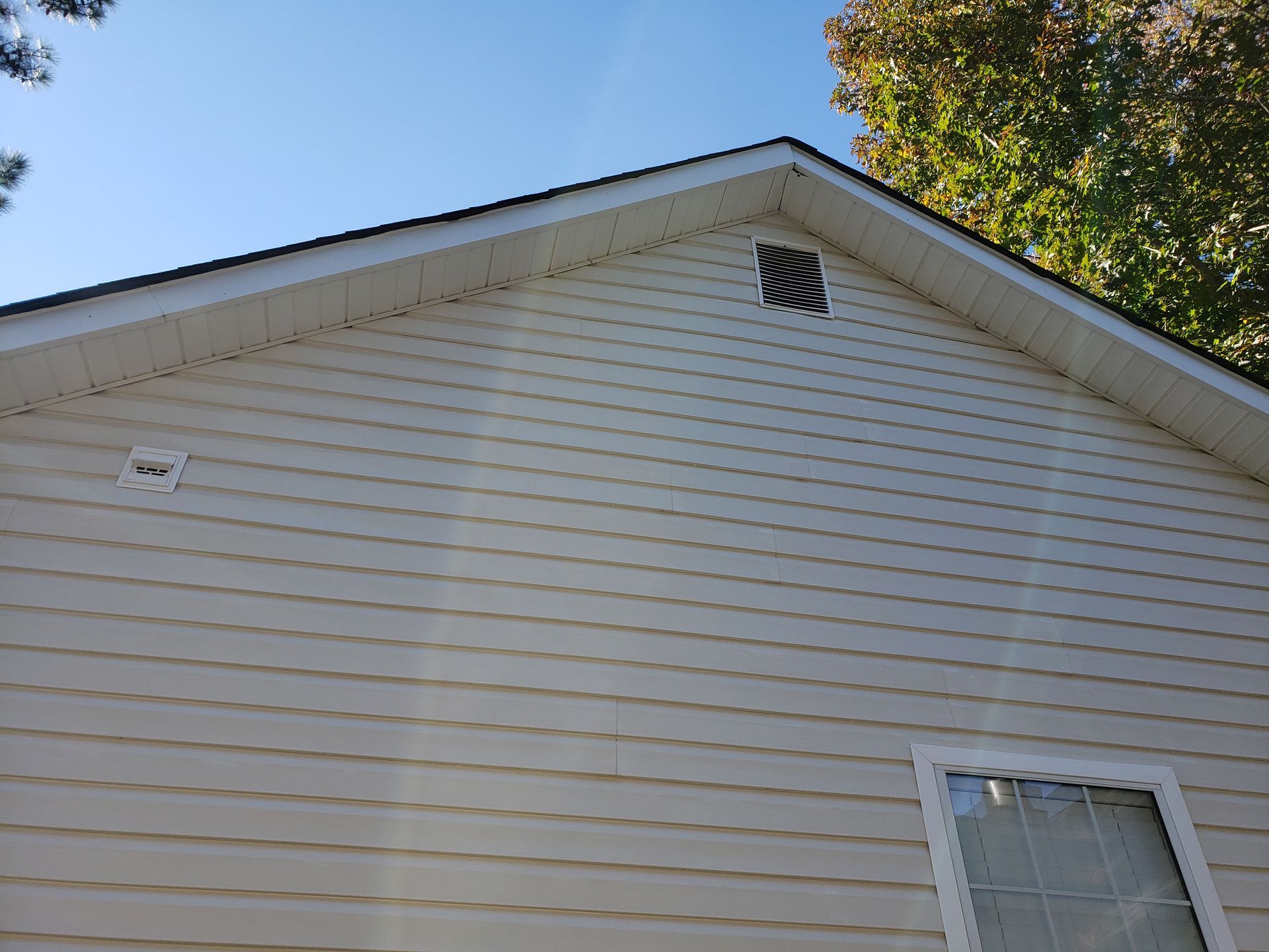 A white house with a black roof and a window.