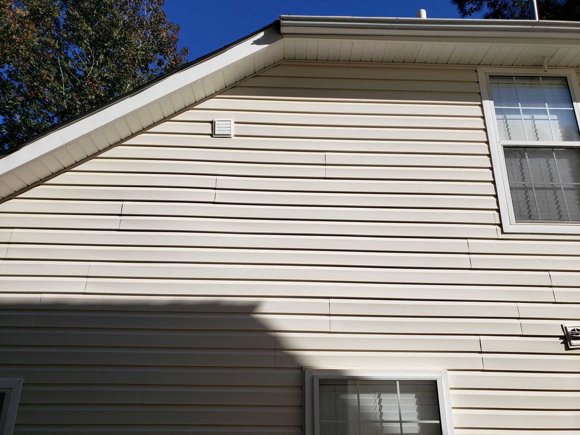 A white house with a window and a blue sky in the background.