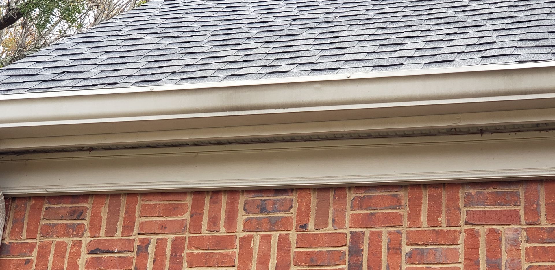 A brick building with a roof and gutter on it.