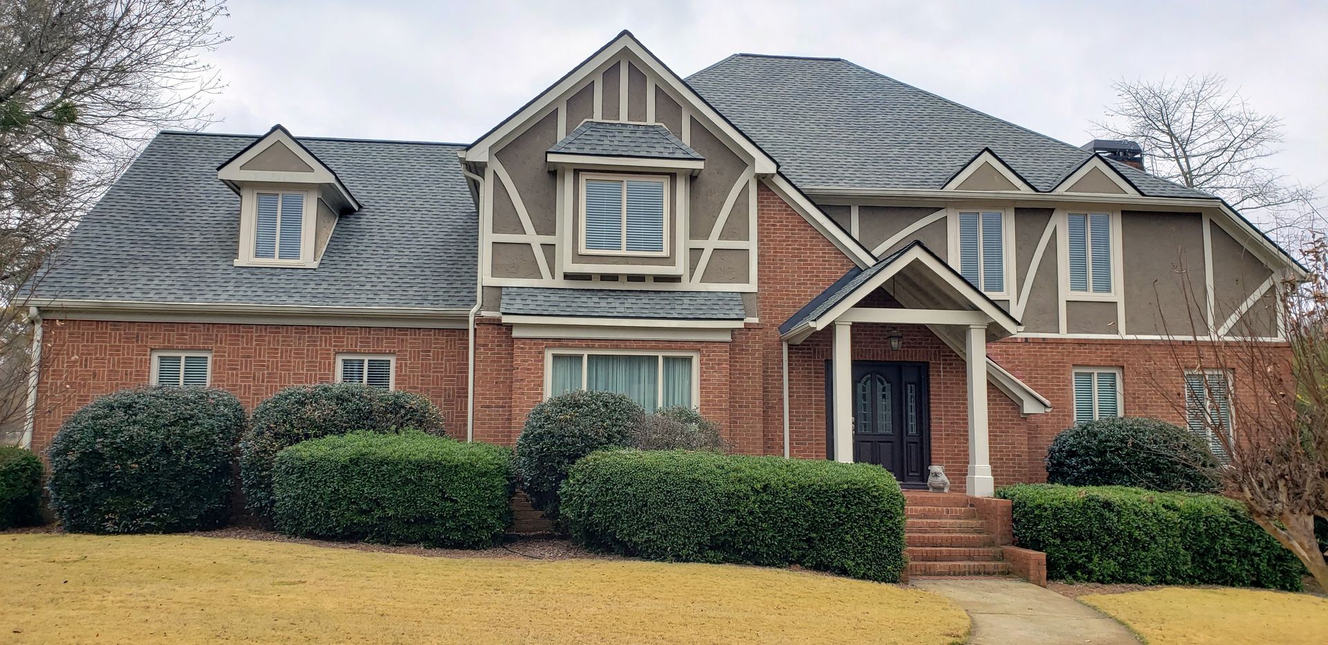A large brick house with a gray roof and a lot of windows
