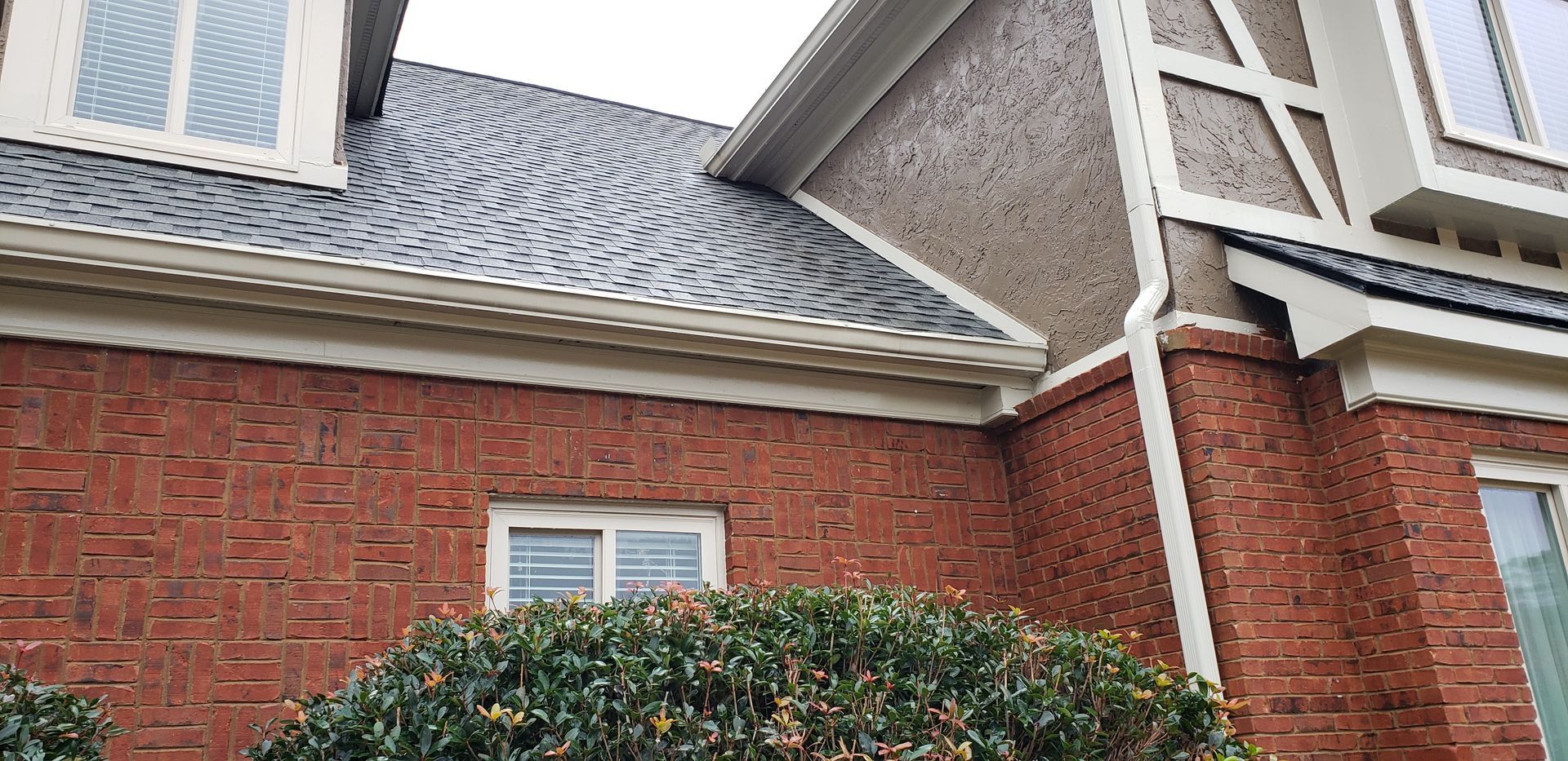 A brick house with a gutter on the side of it.