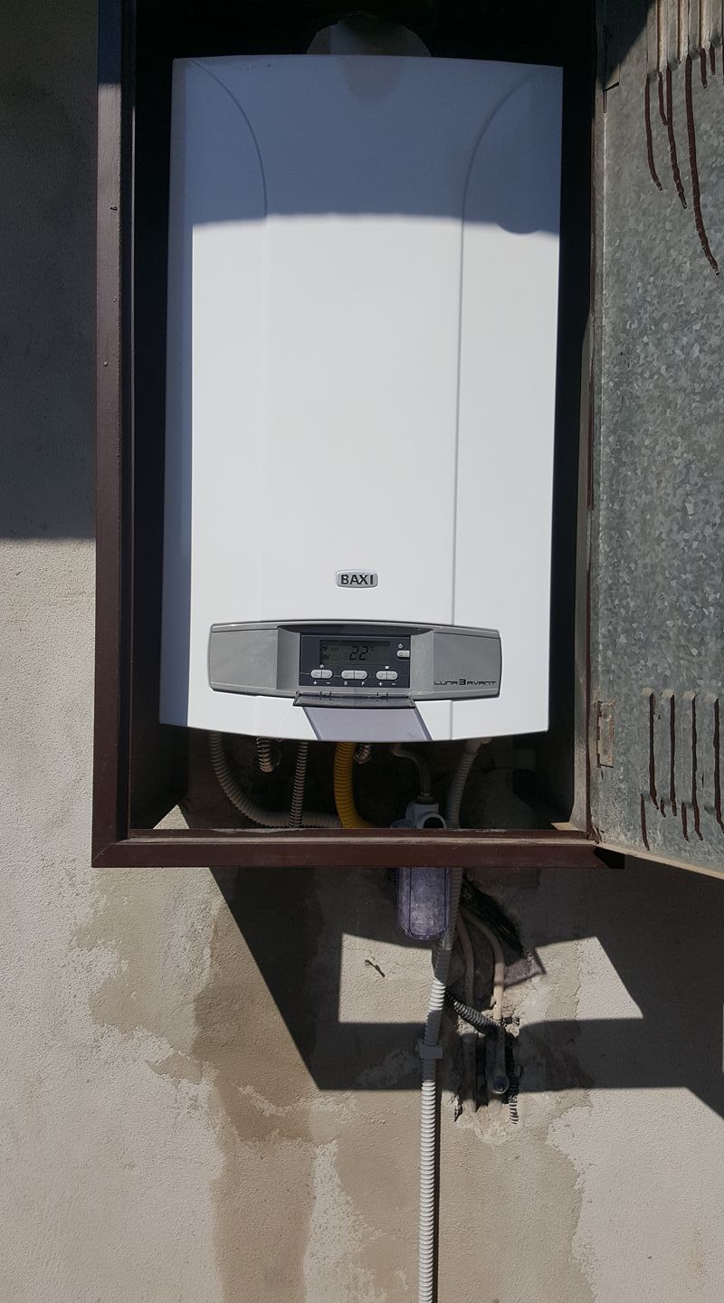 Caldaia a gas bianca montata a parete all'interno di un involucro metallico marrone.