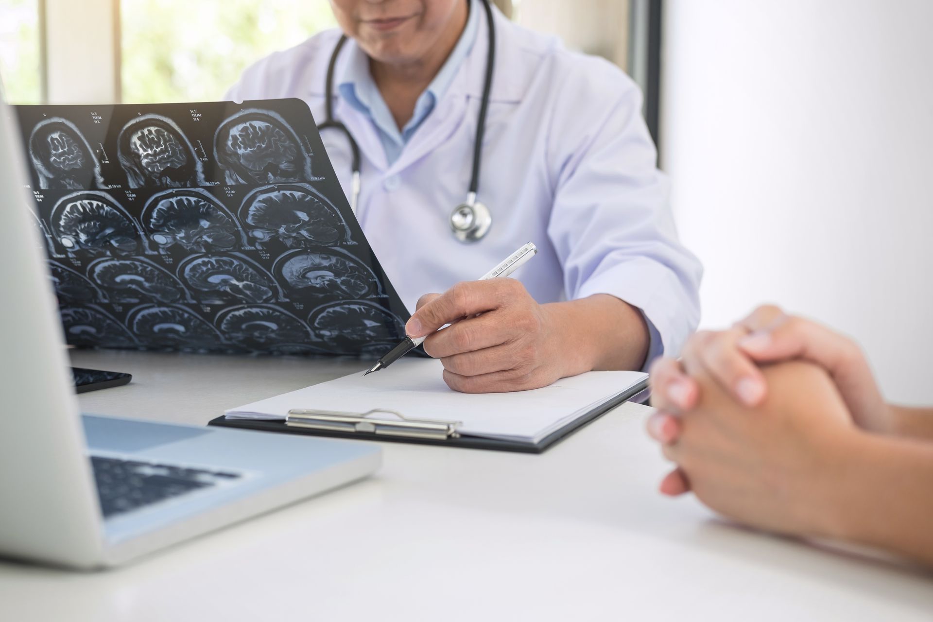 Doctor reviewing brain scan images while consulting with a patient. Doctor reviewing brain scan images while consulting with a patient.