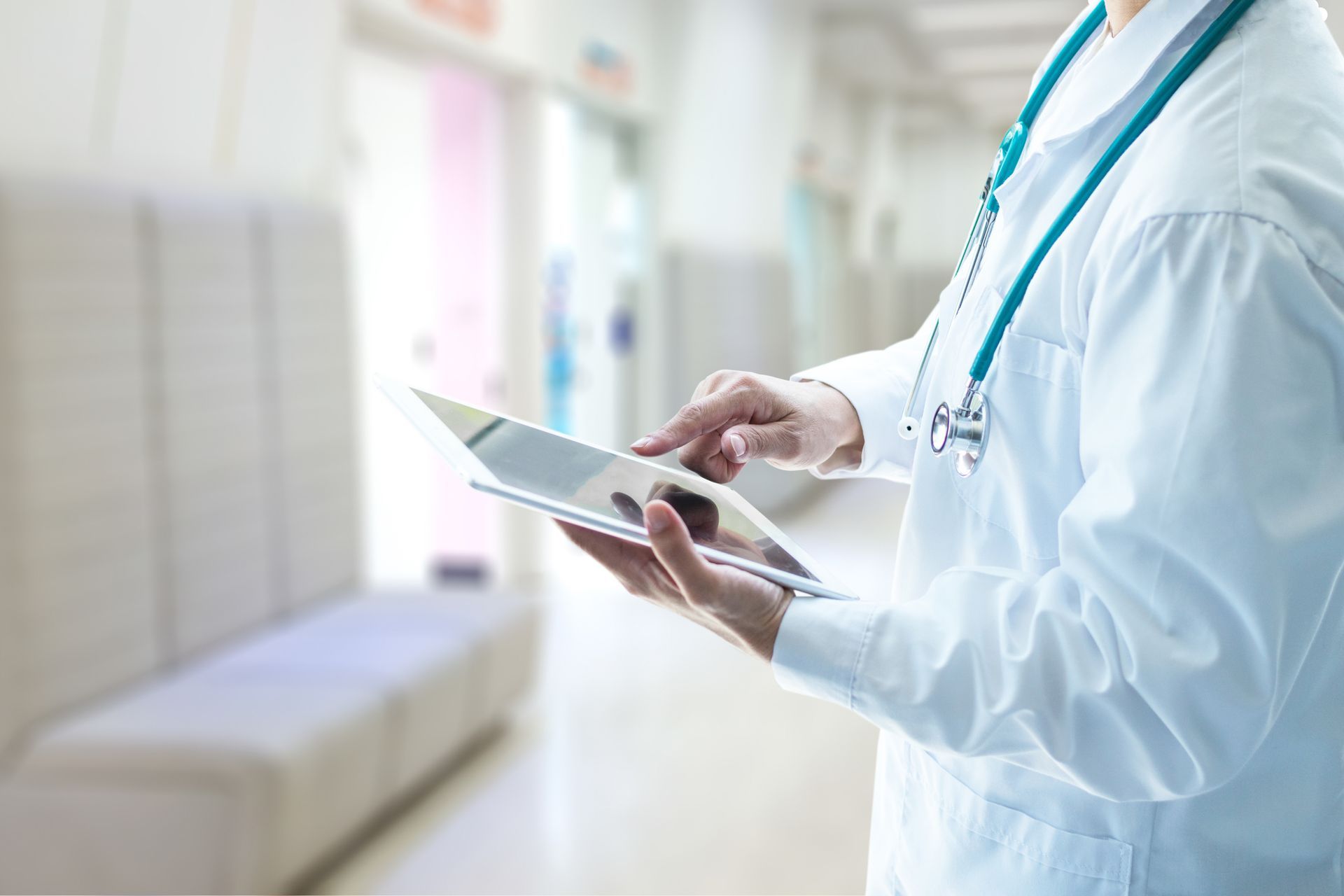 Doctor using tablet in hospital hallway, showcasing digital healthcare technology and innovation.