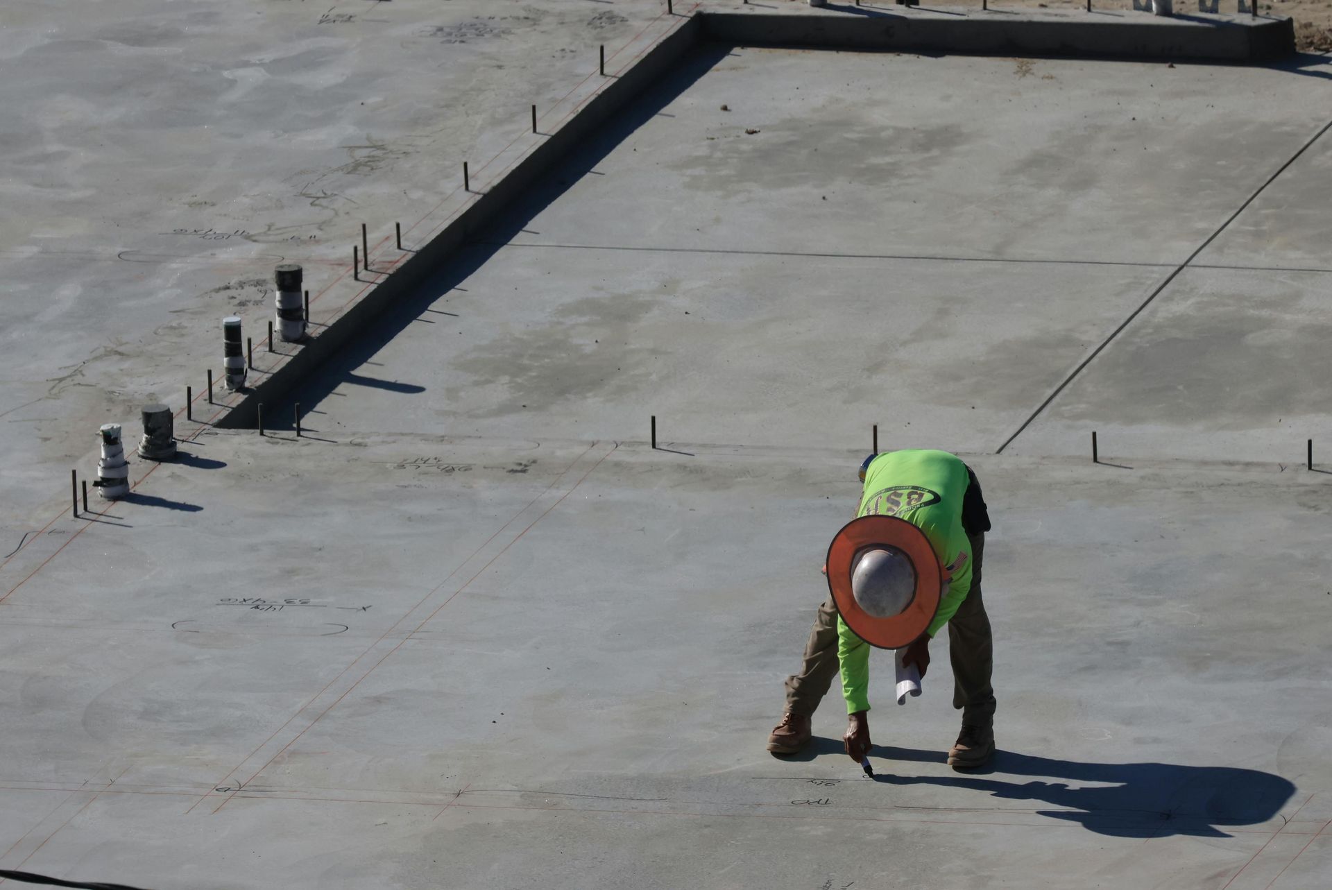 Contractors using tools to compact gravel base for concrete installation