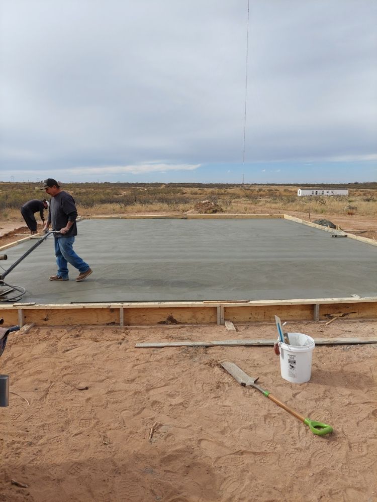 Workers smoothing a concrete slab at a construction site under a cloudy sky