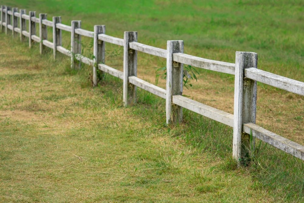 Wooden fence bordering a grassy field.