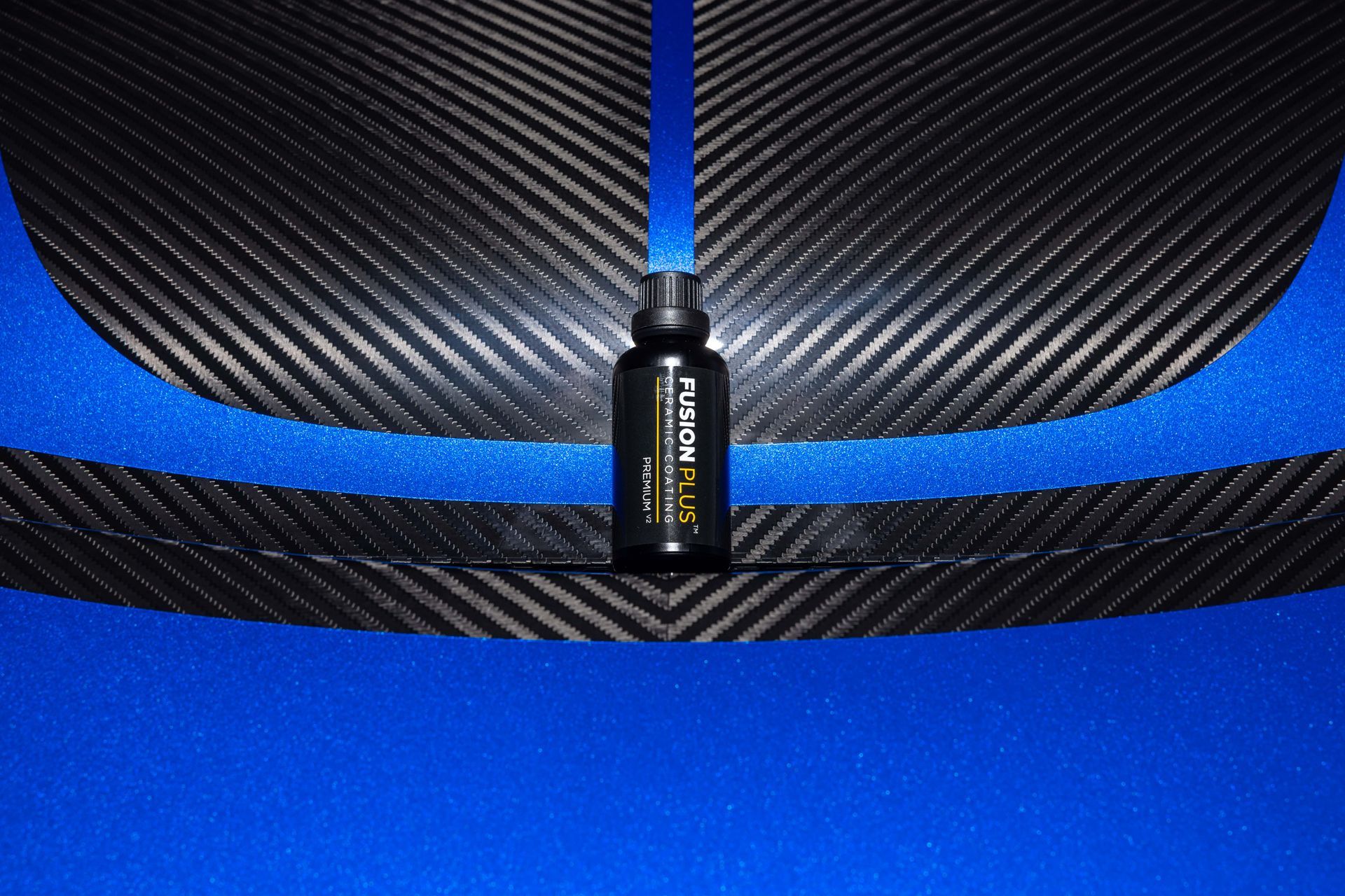 Small black bottle centered on a blue-and-carbon-fiber background