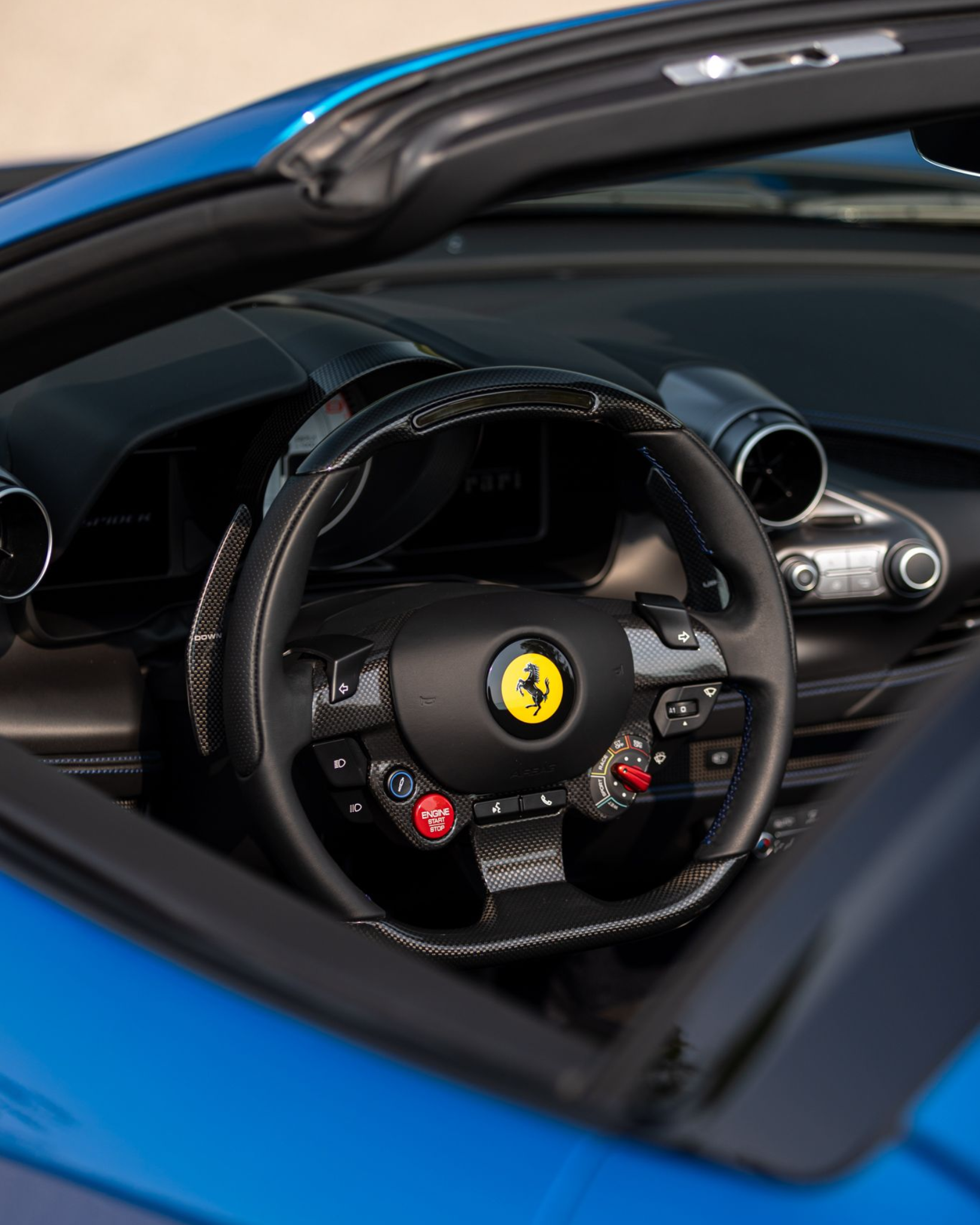 Ferrari sports car interior with carbon-fiber steering wheel and blue exterior trim